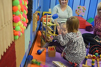 Children using sensory and motor-play materials inside Imagination Station.