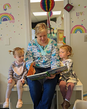 Caregiver reading with two young children inside Island Art Spot
