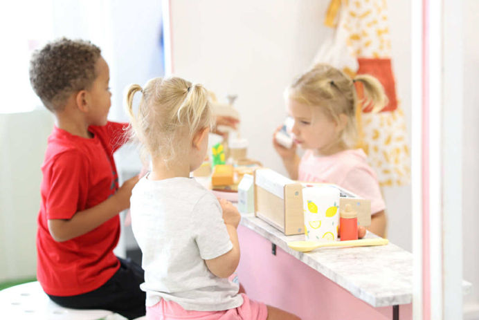 Children using a pretend-play counter area inside J&K Play Studio.