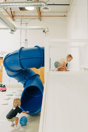 Kids exploring a blue tube slide structure at Jordan's Corner