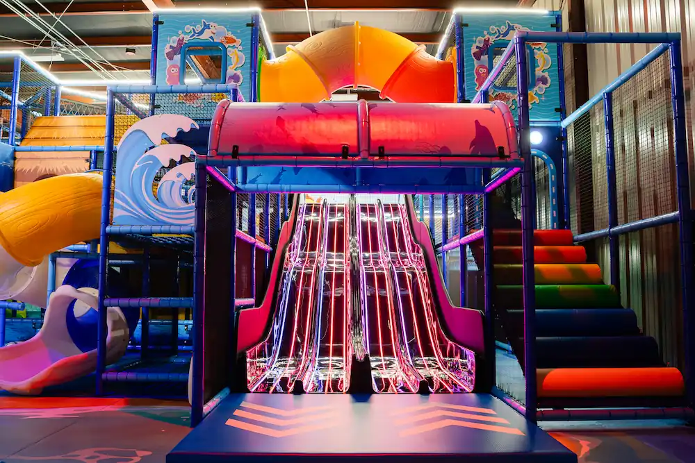 Colorful multi-level indoor playground with slides at Jumpin' Jacks Zone