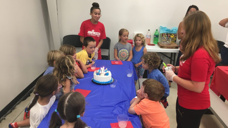 Children gathered with staff during a birthday celebration at Jumpmasters.