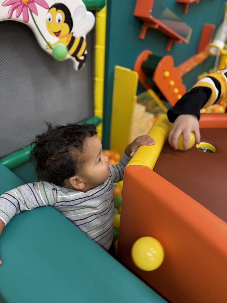 Young child playing beside the ball pit at Kids Play Hive.