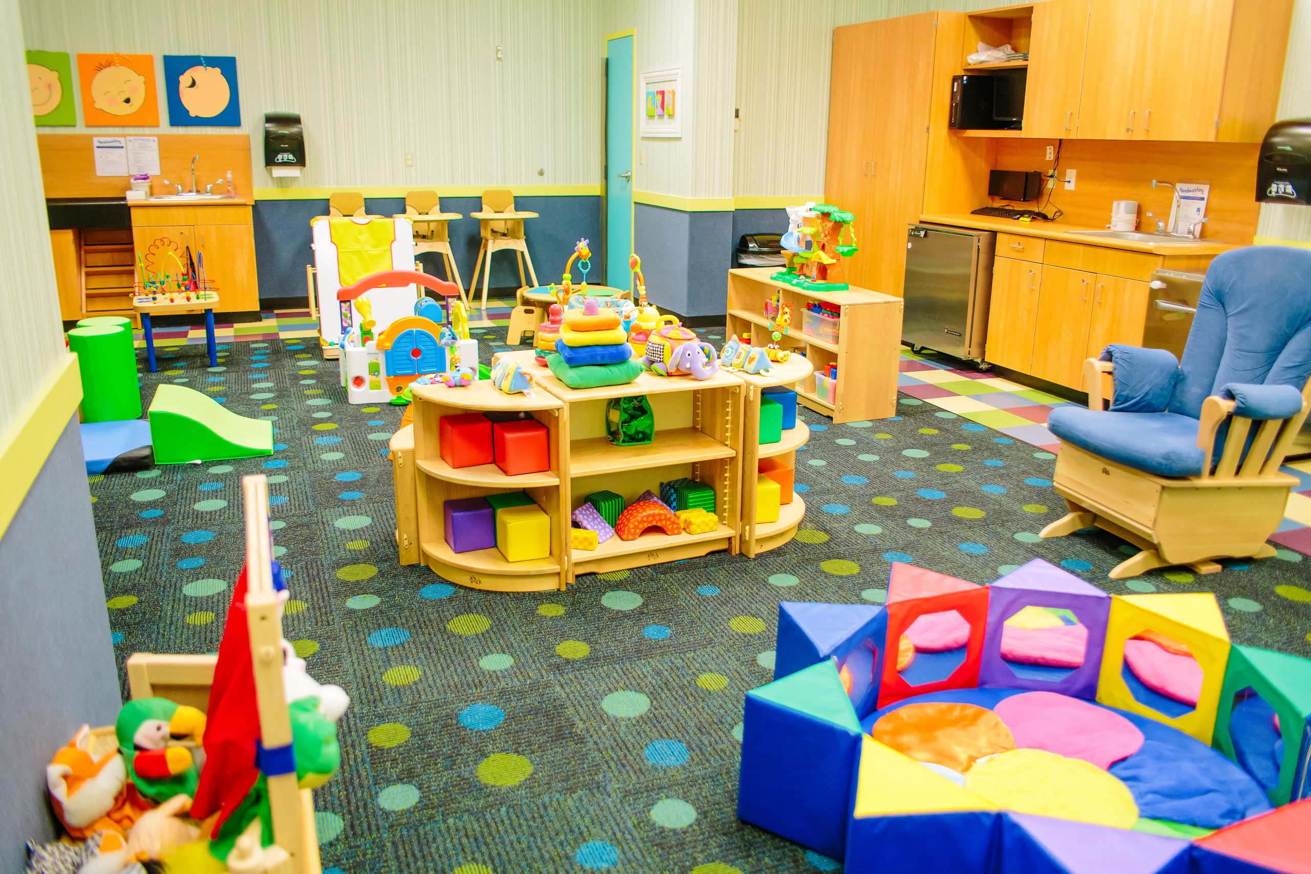 Tiny Tots room at Kids Quest with infant toys, seating, and baby-friendly play equipment.