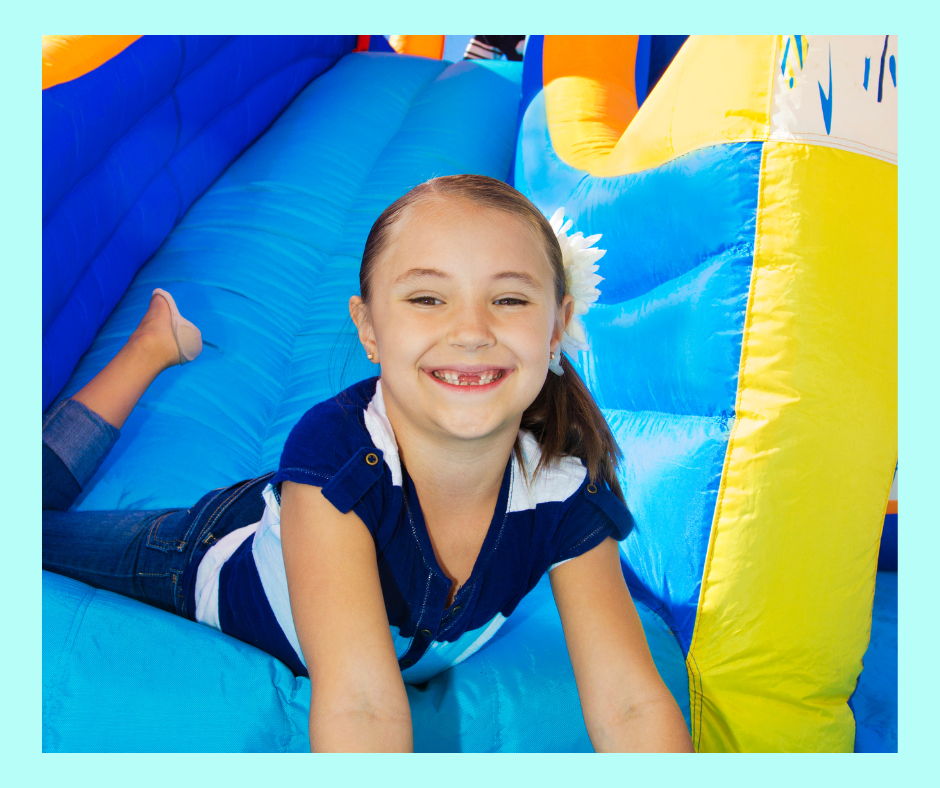 Child smiling on an inflatable slide at Kid's Studio Play.
