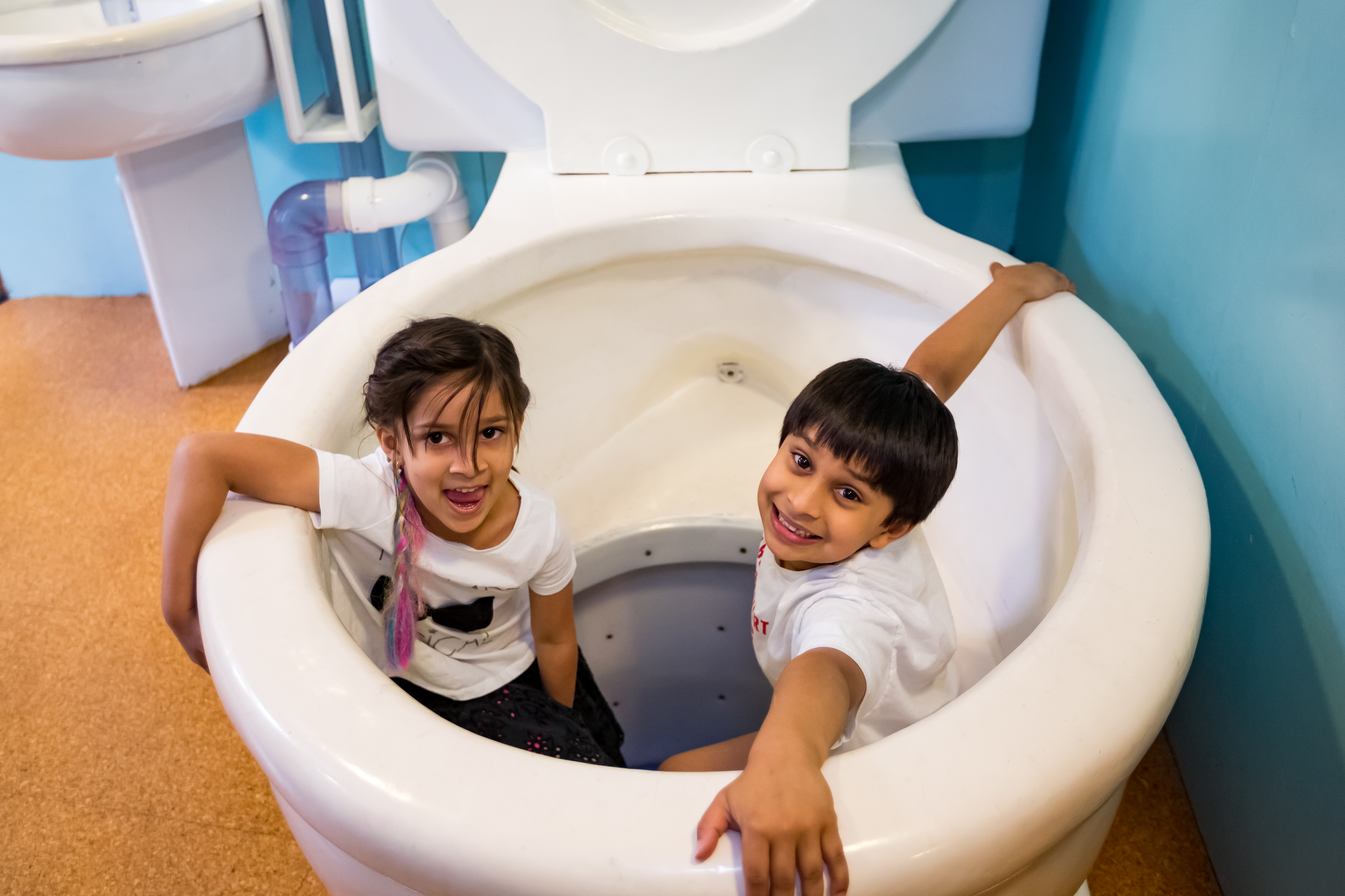Children exploring the giant toilet inside ExploraHouse at kidscommons.