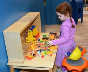 Child using a toy workbench in KidSpace
