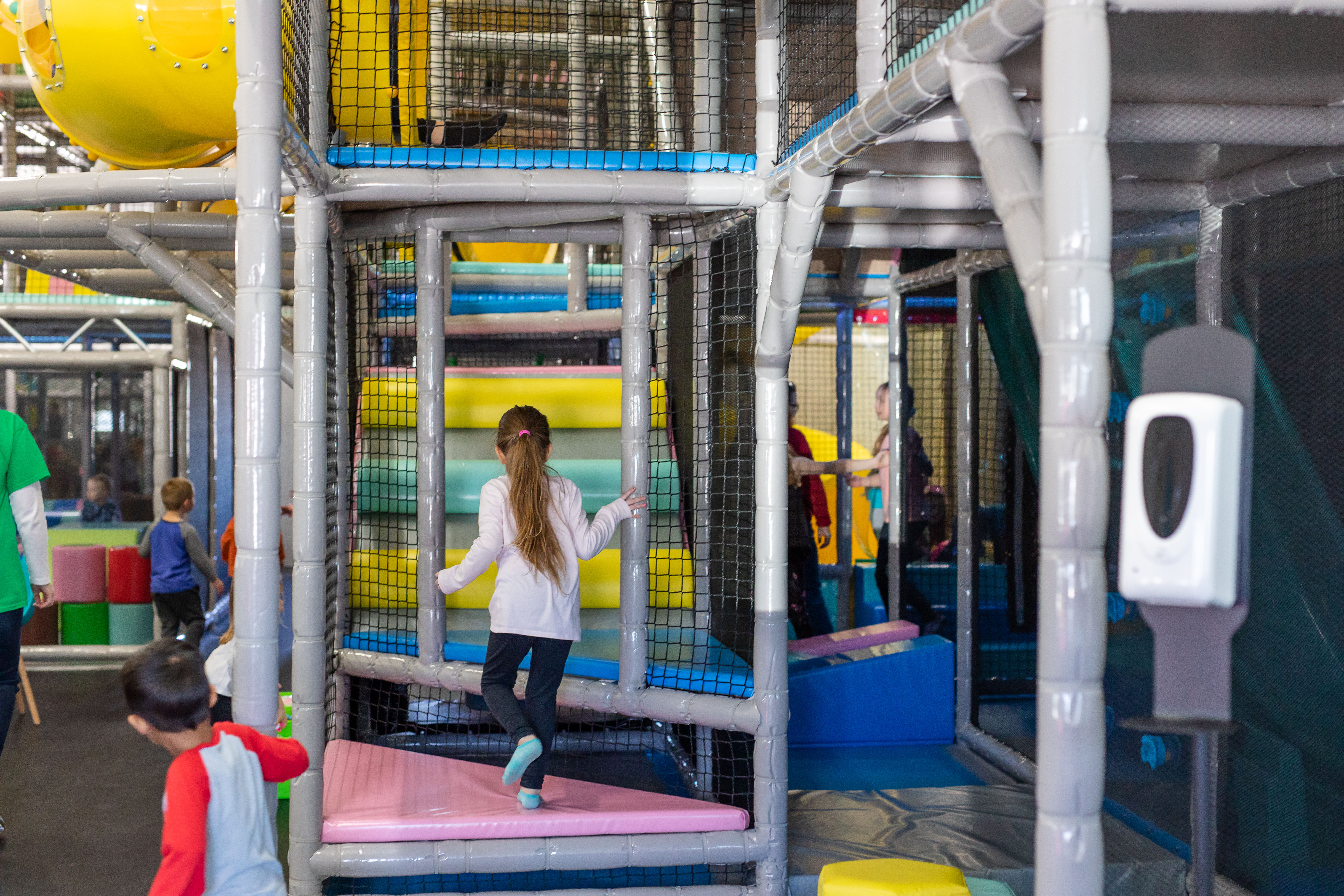 Large indoor play structure with bridges and slides at KinderZone.