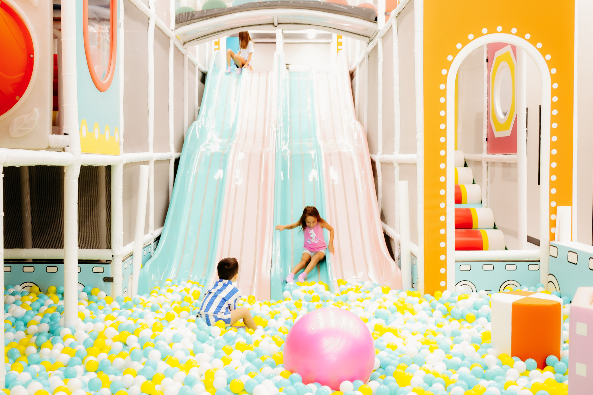 Children playing in the main slide-and-ball-pit area at Lattes & Littles.