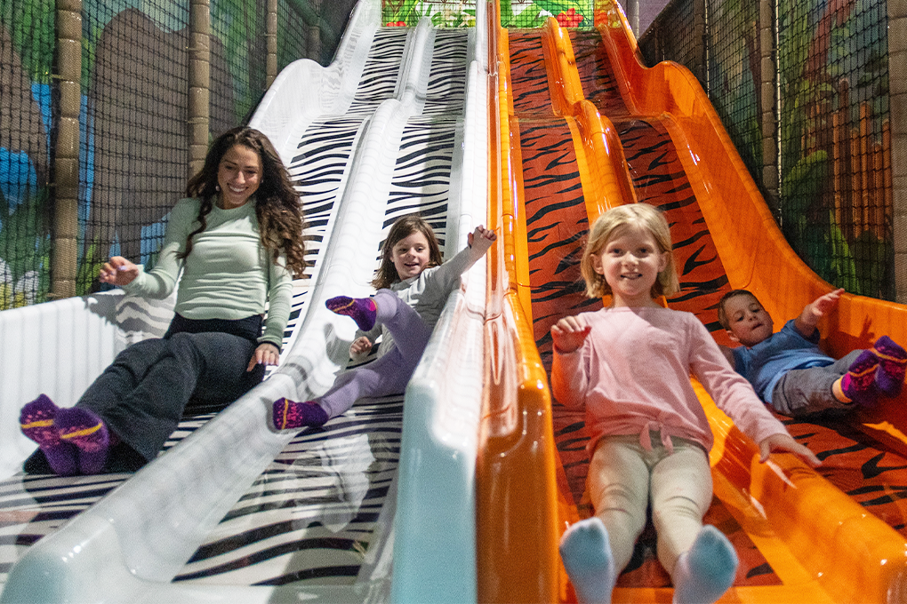 Children on wide indoor slides at Lava Island Manchester.