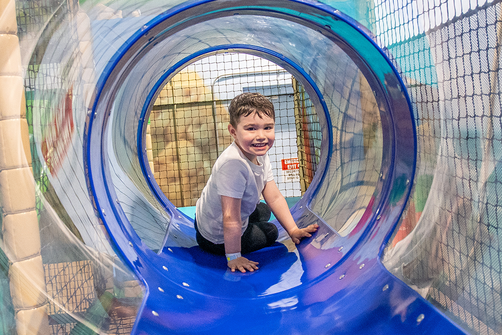 Child in a tunnel play structure at Lava Island Manchester.