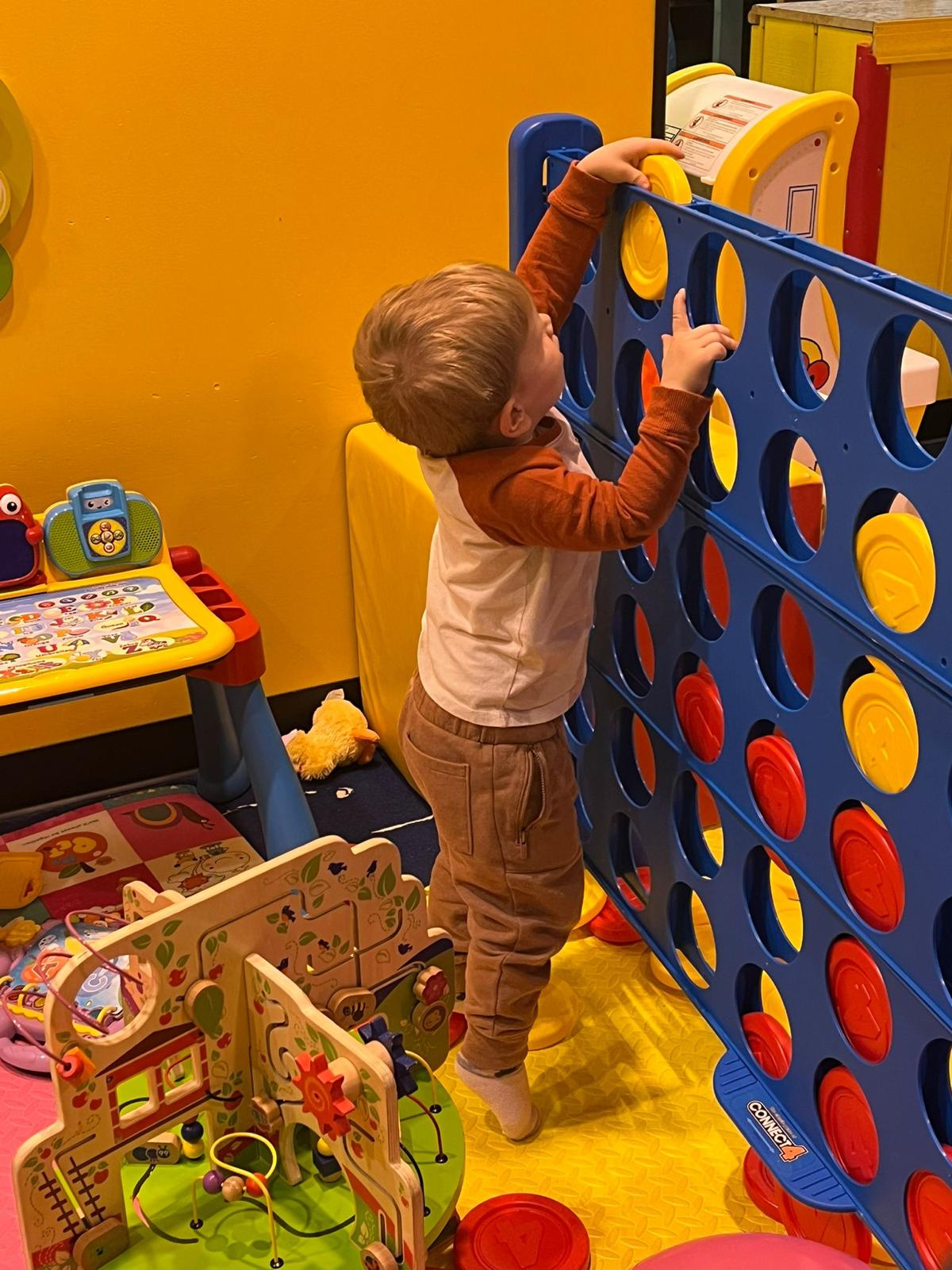 Child playing at an activity wall inside Lil Bunny Play