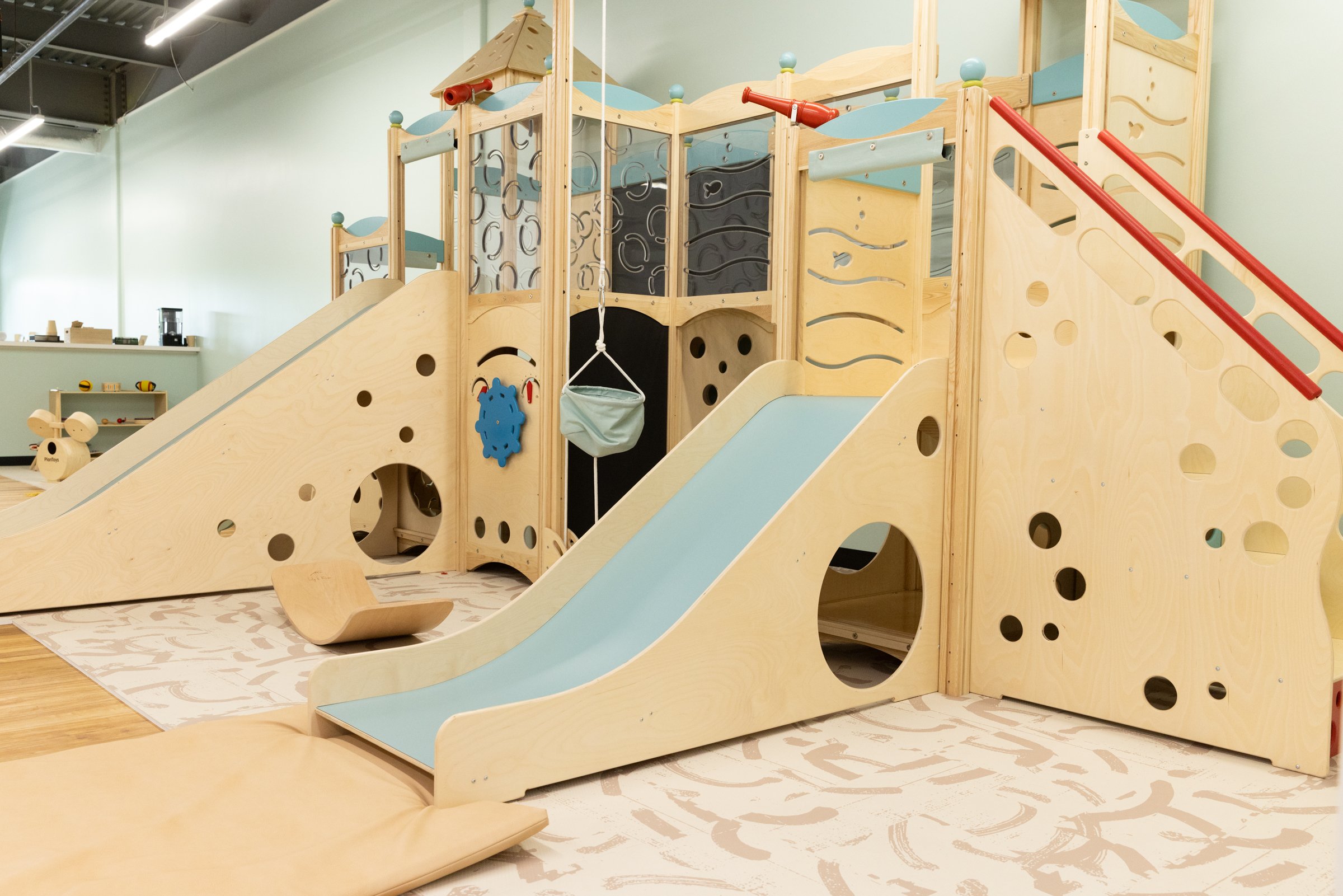 Wooden climbing structure with small slide at Natural Nest Play Cafe Middletown.