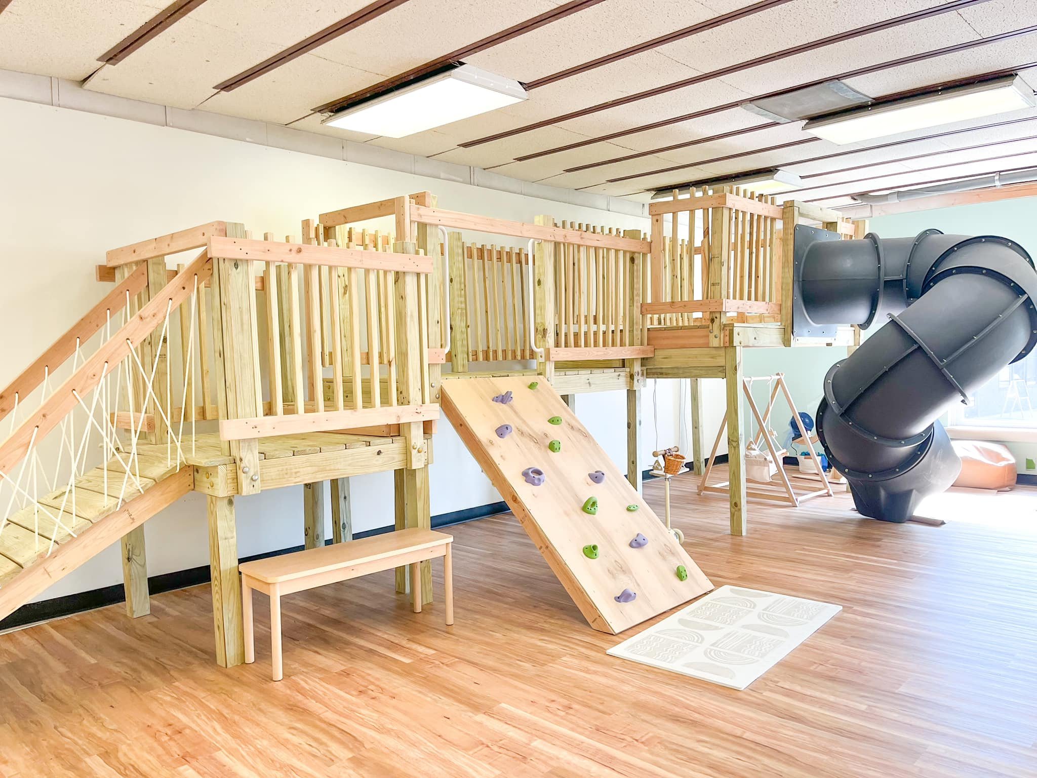 Wooden climbing structure with tube slide at Natural Nest Play Cafe Newark.