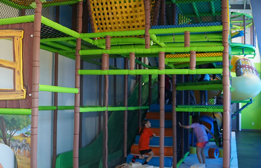 Large enclosed climbing structure with slides inside NLCC PlayZone.