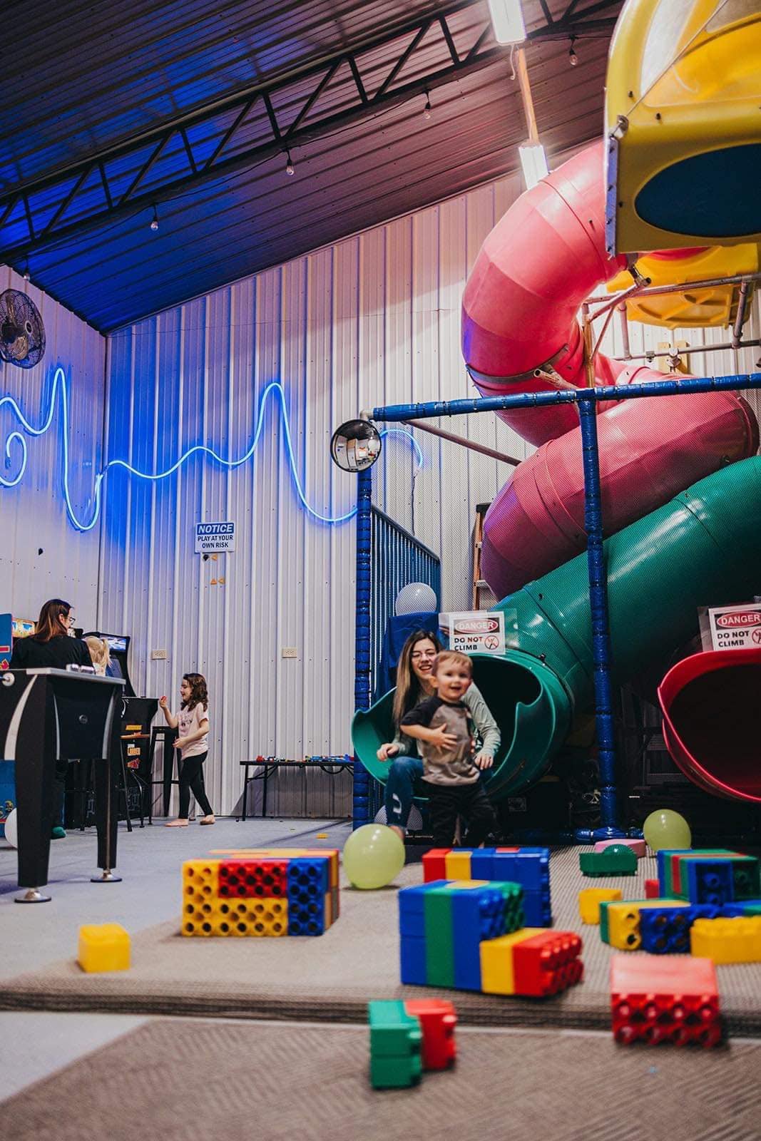 Large indoor slide structure and arcade area at Party Barn.