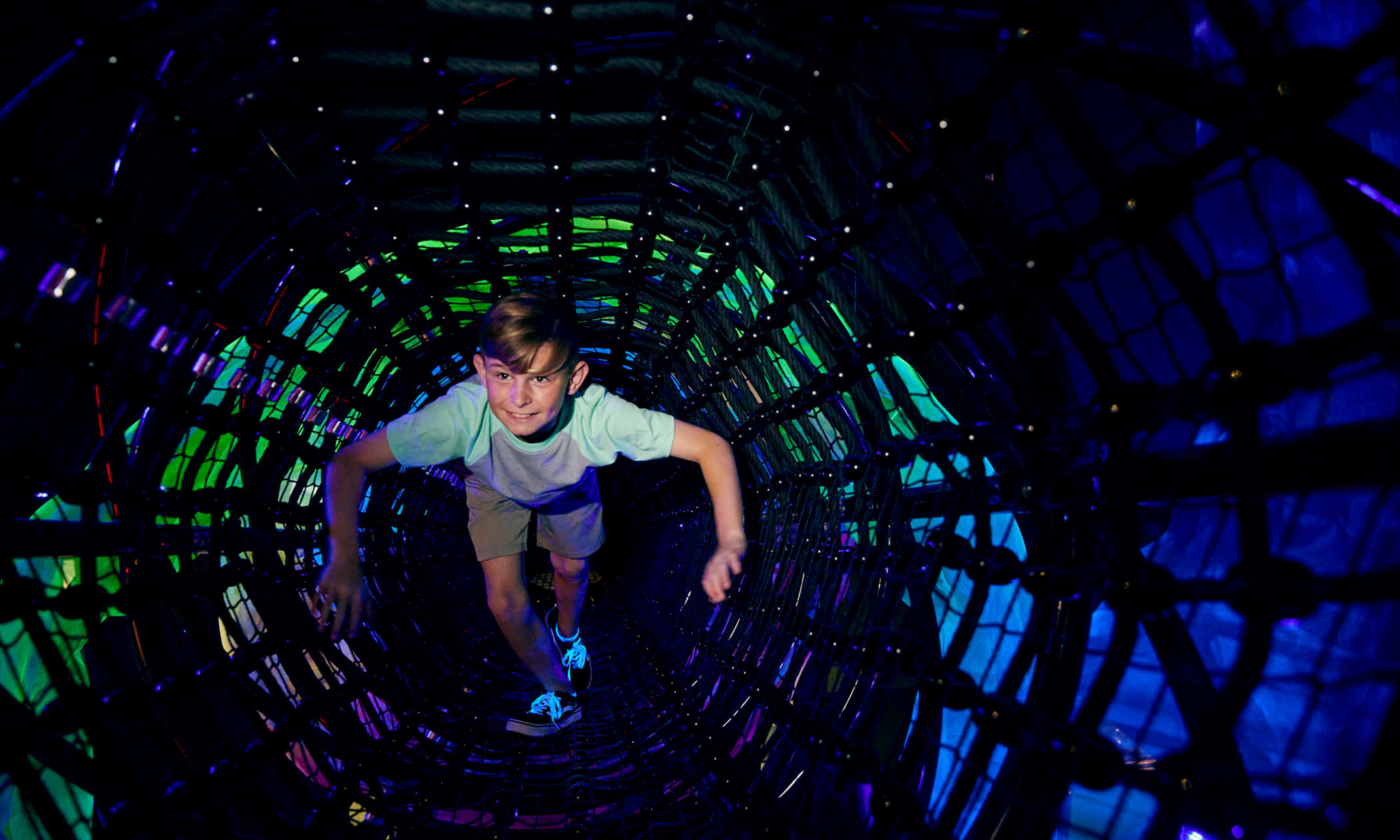 Child climbing through the wormhole play feature at Planet Play.