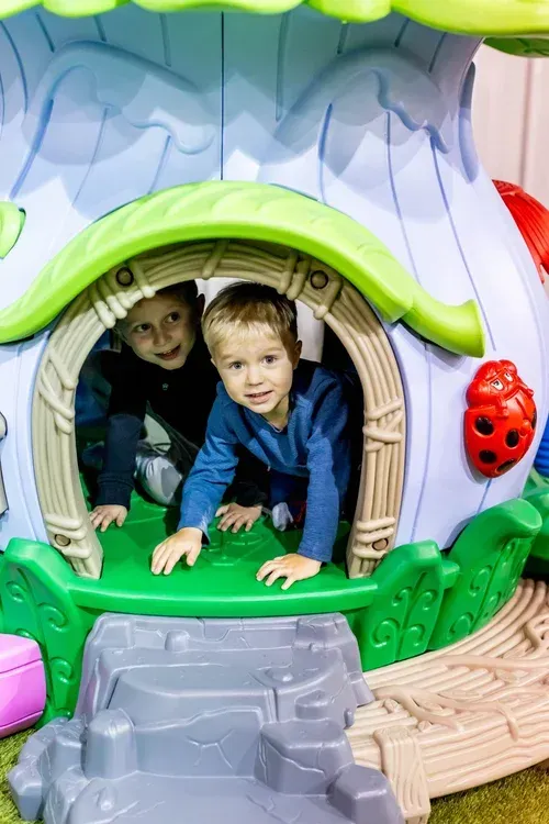 Young children crawling through a playhouse in the toddler area at Play Grounds of La Crosse.