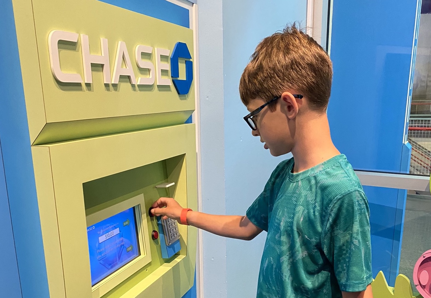 Child using the bank-style pretend-play exhibit at PoP Children’s Museum.