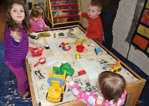 Children gathered around a sensory table at Preschool Play World in Newport.