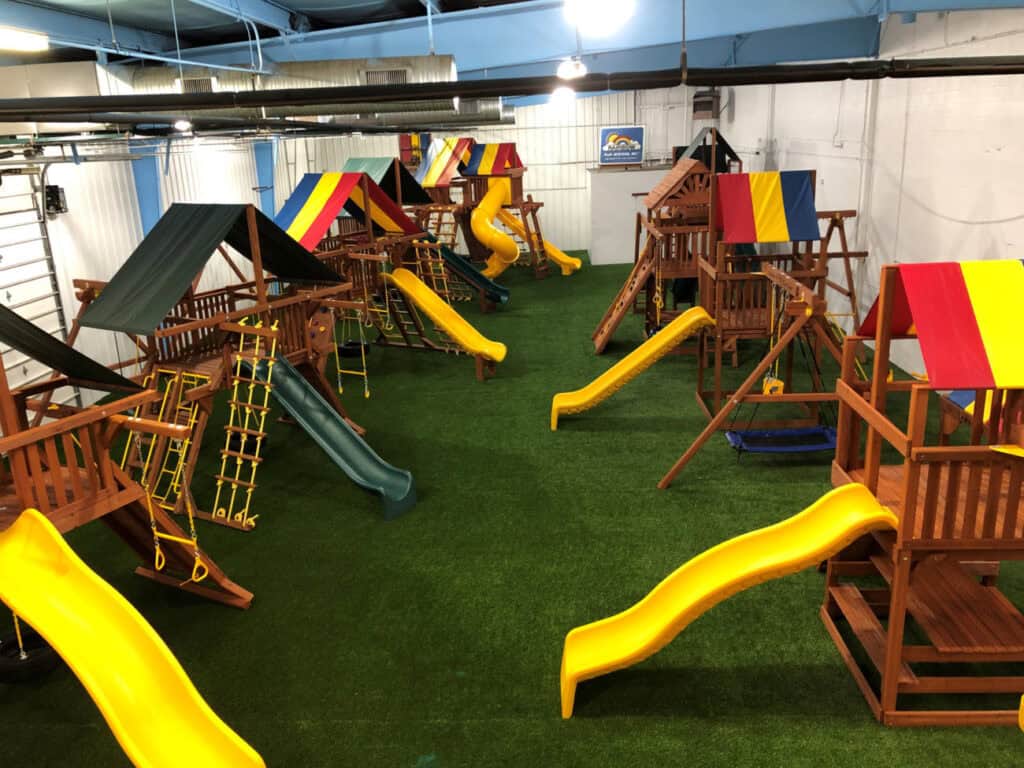 Large indoor showroom floor with multiple Rainbow playsets.