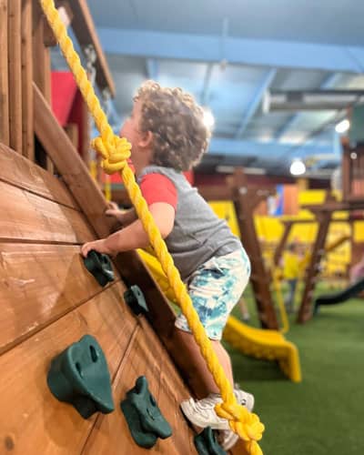 Child climbing on an indoor showroom playset at Rainbow of the Heartland.