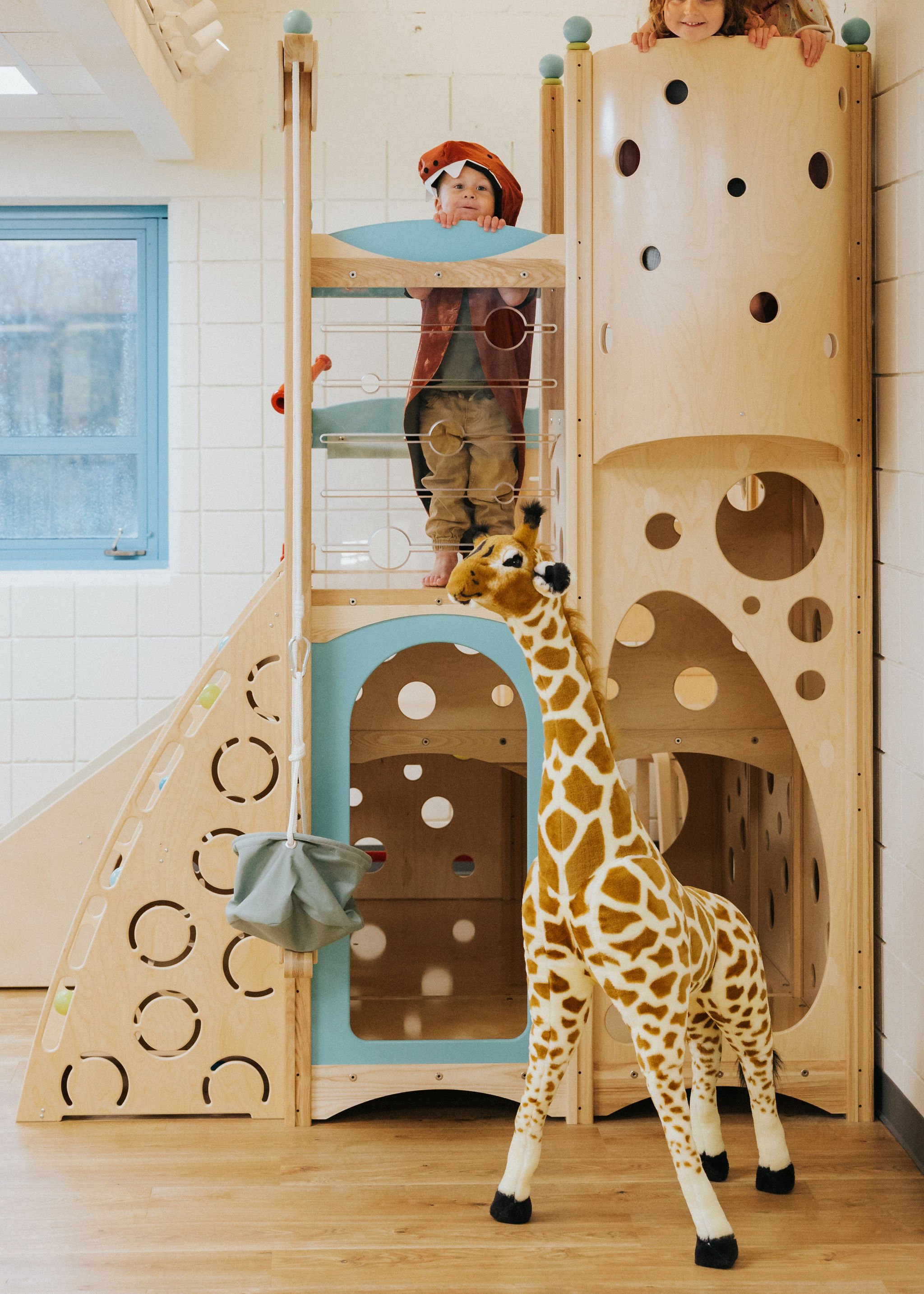 Child using the wooden climber at Raise Playspace.