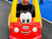 Child sitting in a Little Tikes Cozy Coupe toy car at Recreation Station.