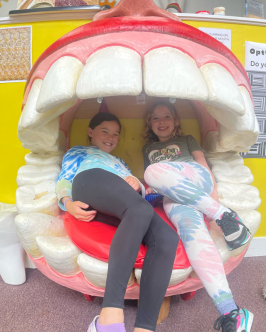 Two children sitting in a giant mouth exhibit at Redwood Discovery Museum