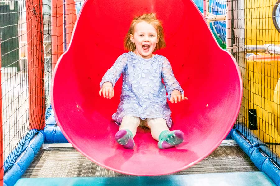 Child coming down the slide in the Ridge Kids Playzone at Ridge Athletic Club in Bozeman