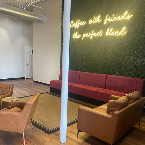 Lounge seating area with a neon sign at run+play kids cafe.