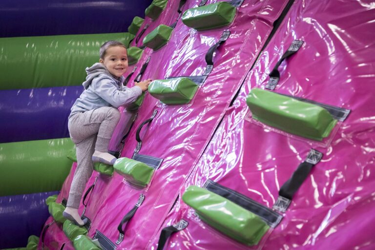 Child climbing the inflatable wall inside a Ryan's airpark.