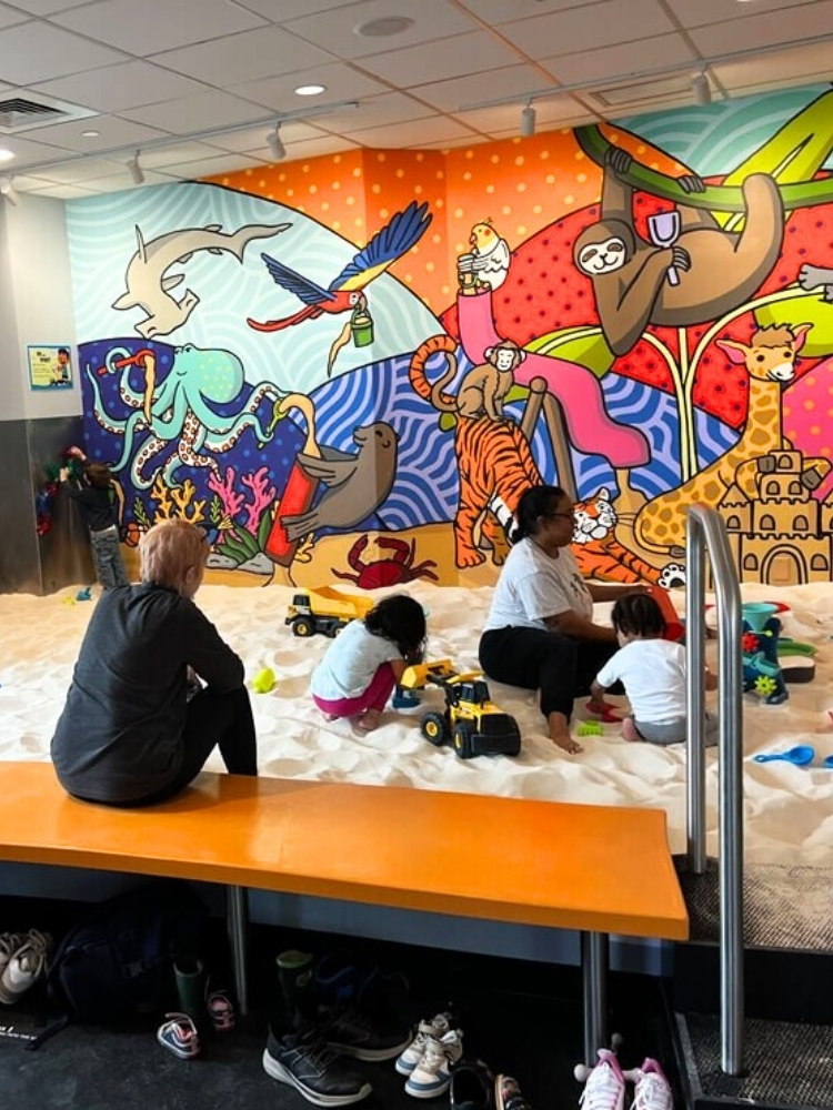 Children and caregivers in the indoor sandbox at Sandmagination