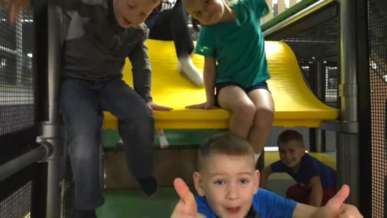 Children playing on the yellow slide platform at Hangtime Jr