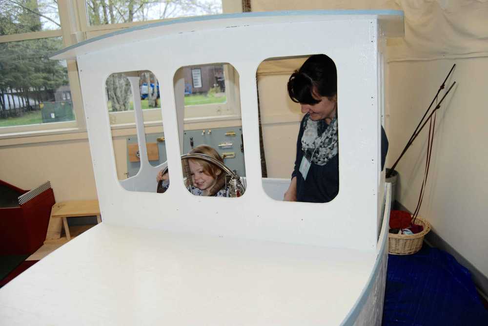Child and caregiver at the white boat play structure inside Sitka Children's Museum.