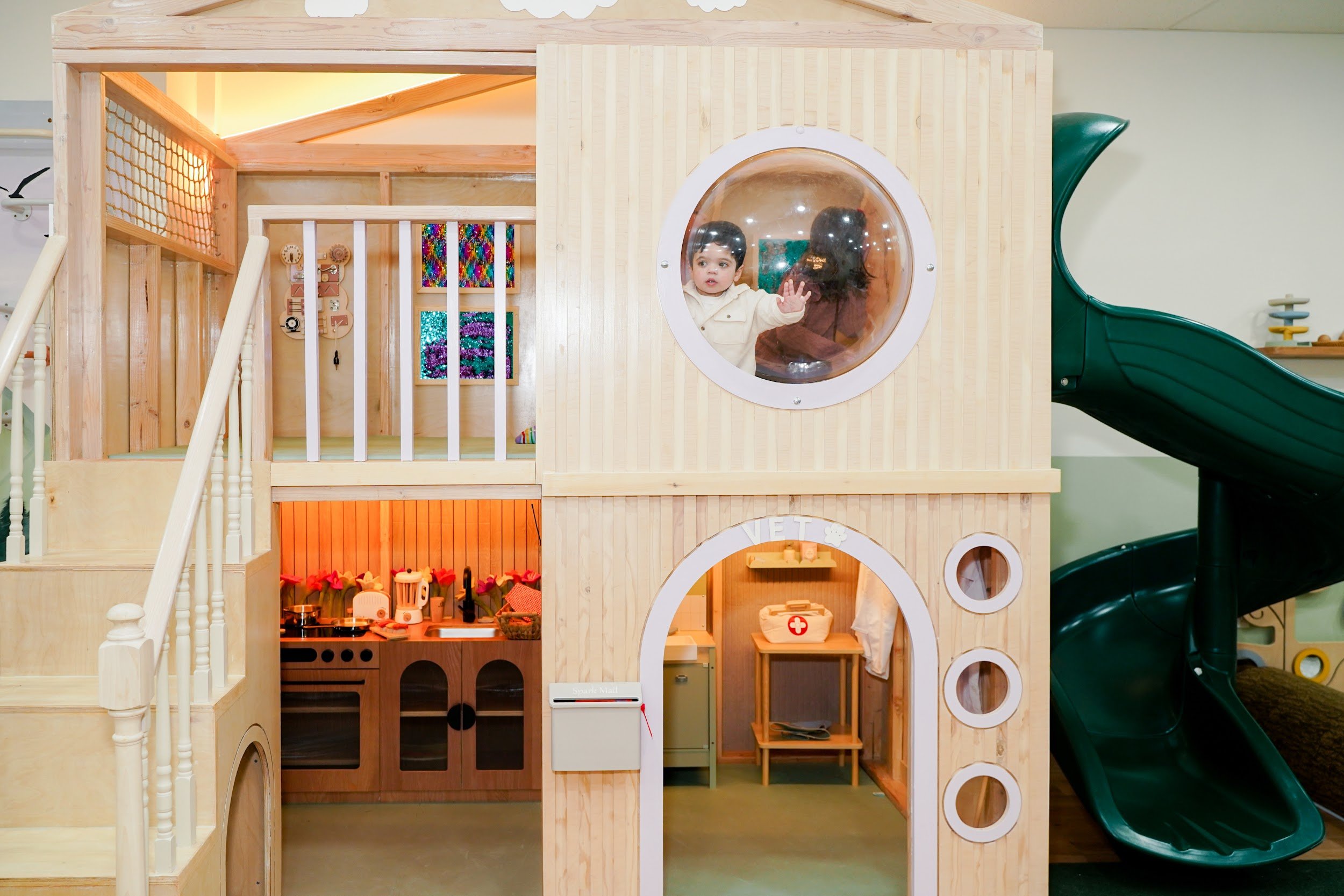 Wooden playhouse and green slide inside Spark Place in Jersey City.