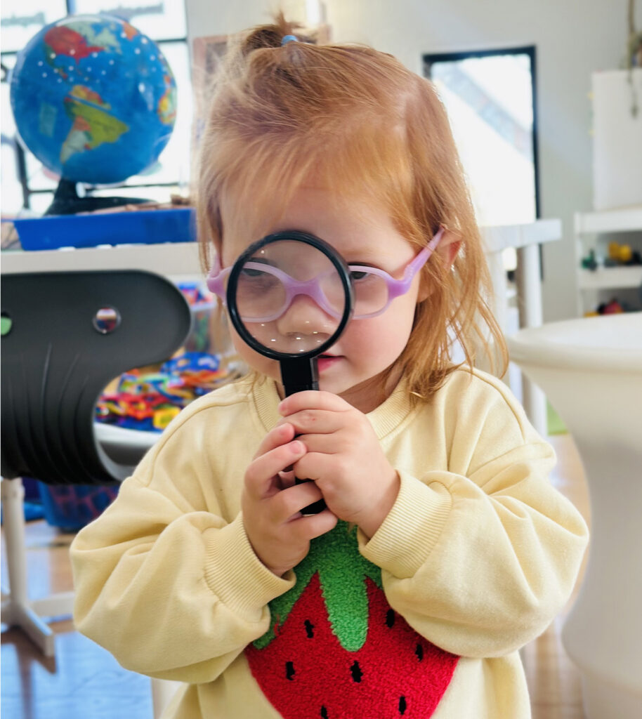 Child using a magnifying glass at Stemville Howell.
