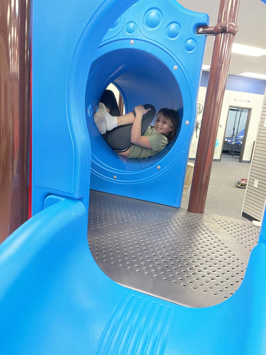 Child playing inside the blue tunnel section of the main structure at Superior Funland