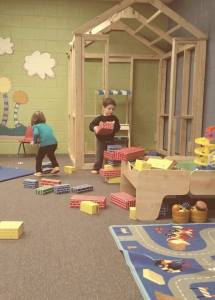 Children playing with large blocks in a pretend-play area at Superior Playland.