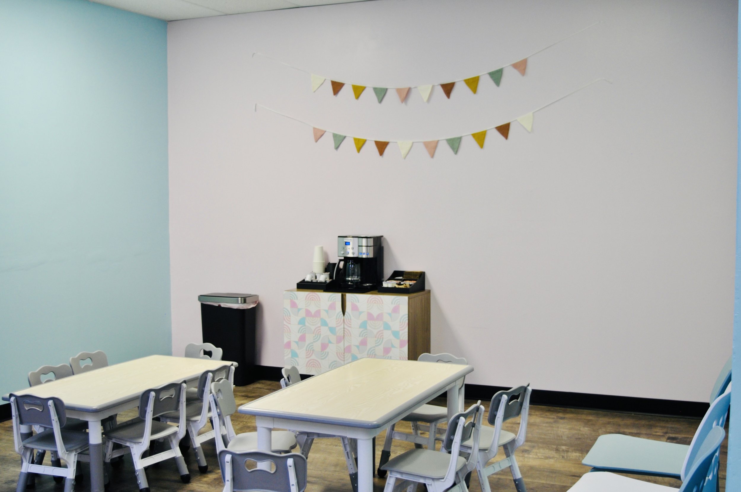 Caregiver seating area with tables and coffee setup at The Beach House Play Center.