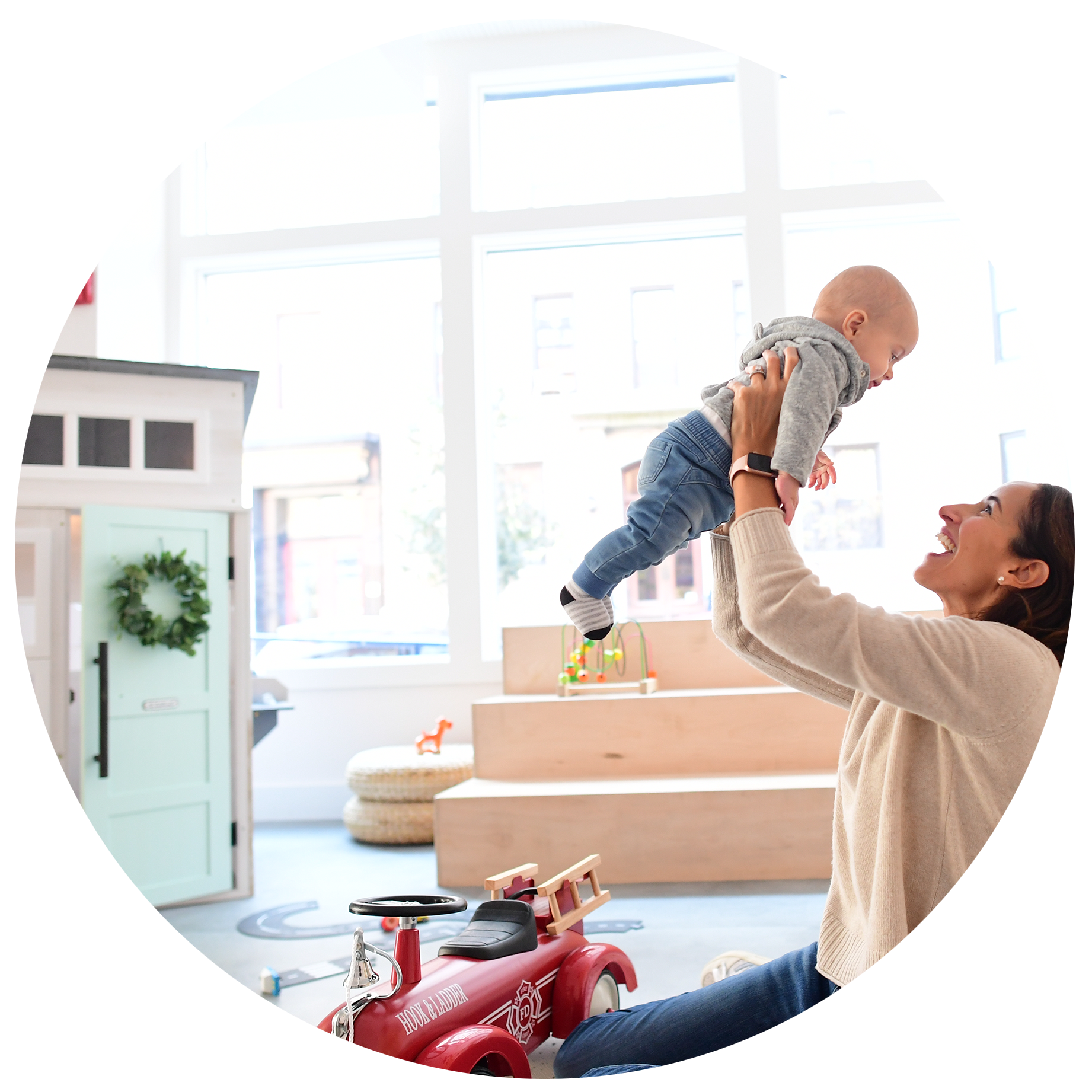 Caregiver lifting a baby in the play area at The Hive.