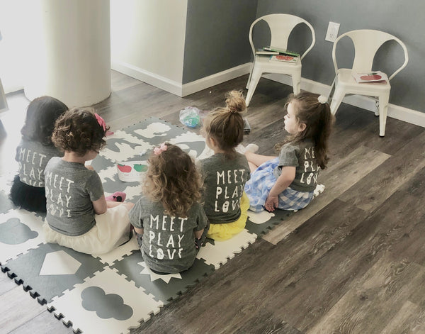 Young children sitting together during a small group activity at The Little Play Co.
