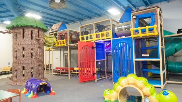 Multi-level indoor climbing structure and tree-house play area at The Playground for Kids.