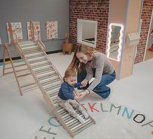 Young child using a small climbing feature inside The Playroom in Morgantown.