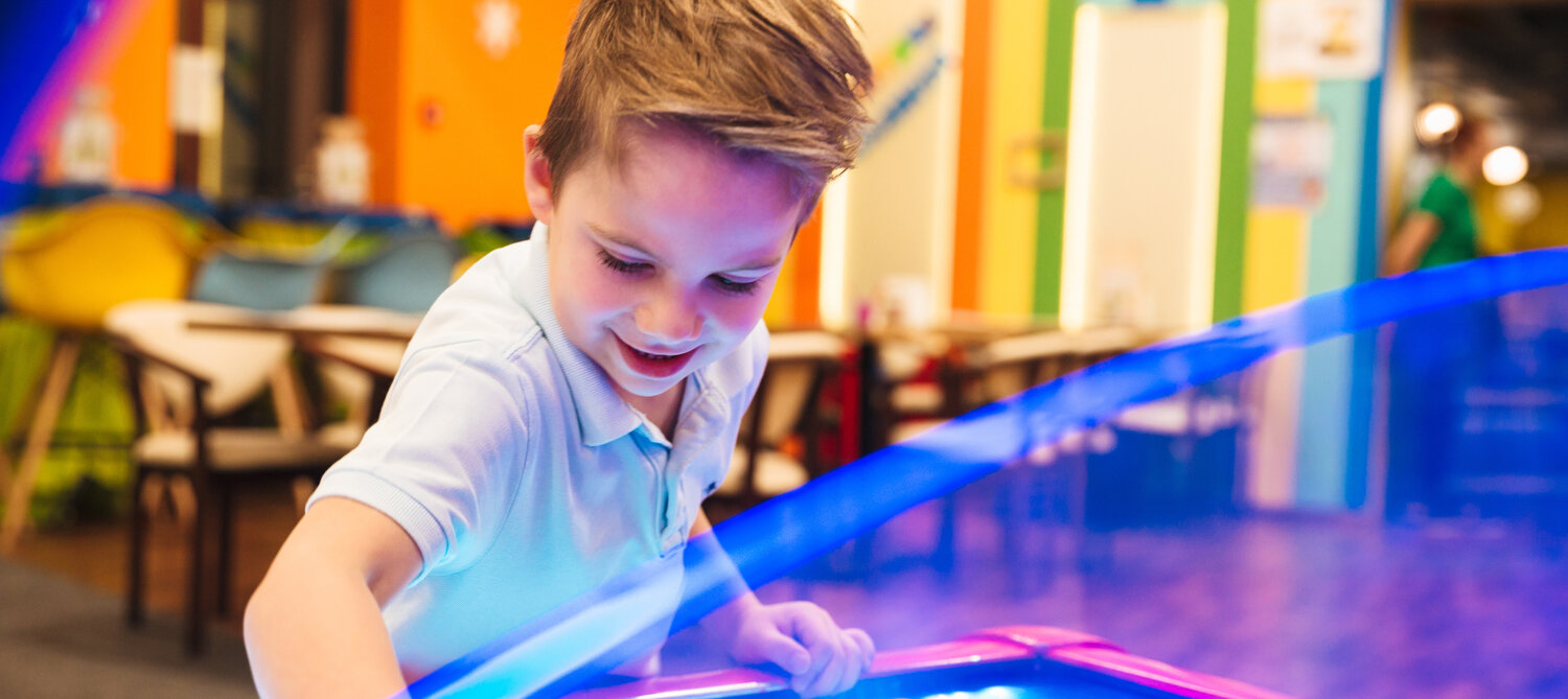 Child using an activity table inside The Social Club.