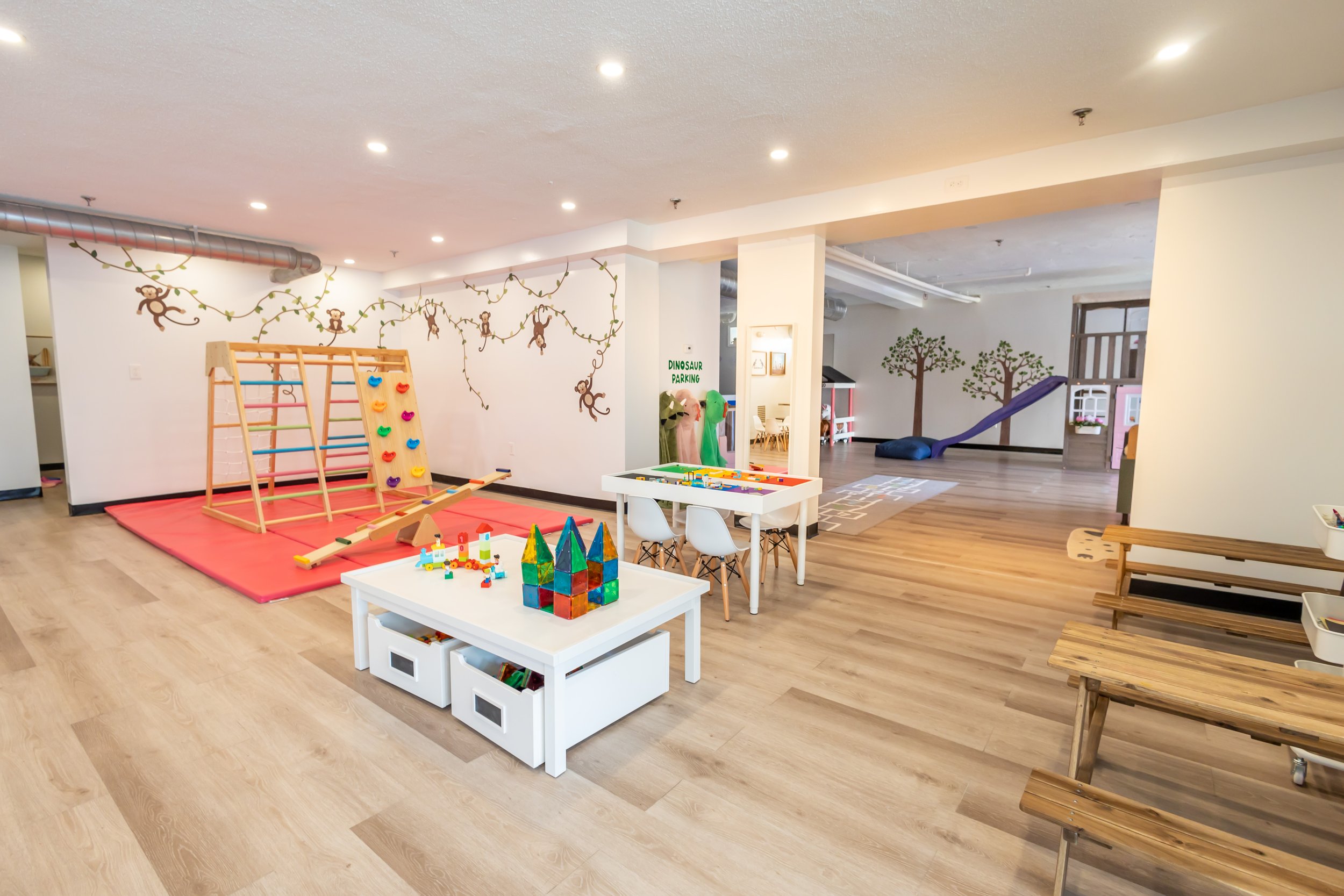 Bright indoor playroom with climbing, sensory, and pretend-play setups at The Village Playspace in Medford.