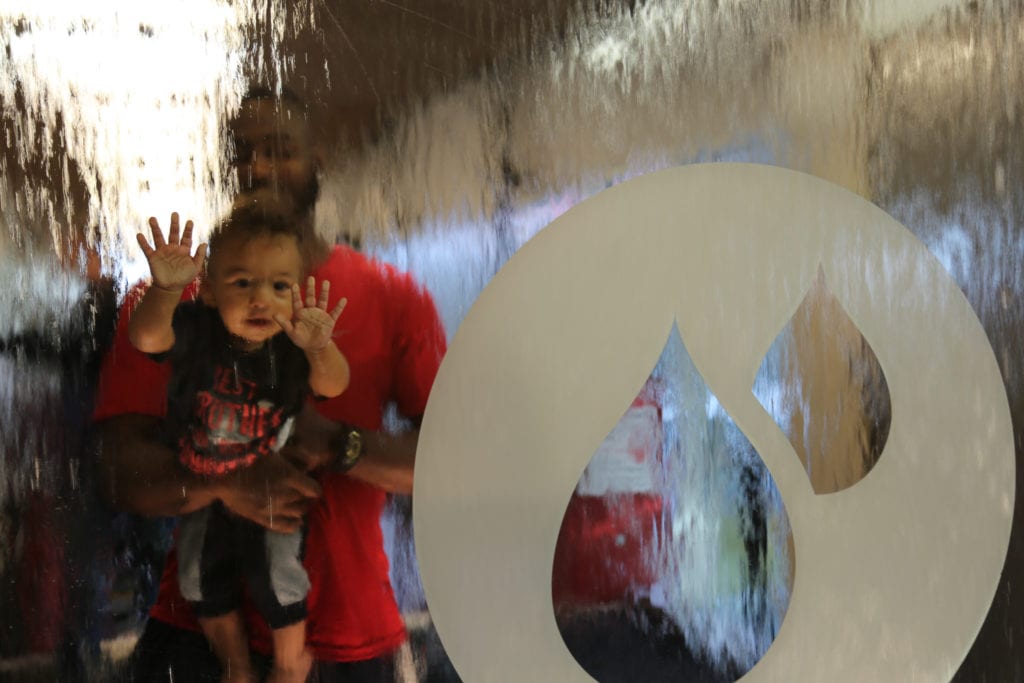 Children and caregivers using hands-on museum exhibits inside Thinkery.