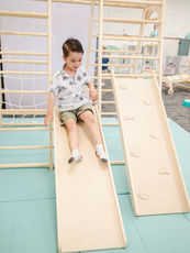 Child sliding on the indoor play equipment at Tiny Beans Play Cafe