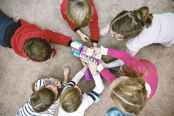 Children sitting together on the floor around block toys at a Florida Keys Healthy Start playgroup.