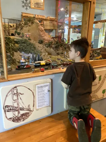Child watching a large model railroad exhibit inside the museum.